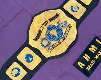 May include: A black leather championship wrestling belt featuring a large gold center plate with blue globe inlays and the text WORLD HEAVYWEIGHT WRESTLING CHAMPION. The belt includes smaller gold side plates with blue globe designs and a black tag.