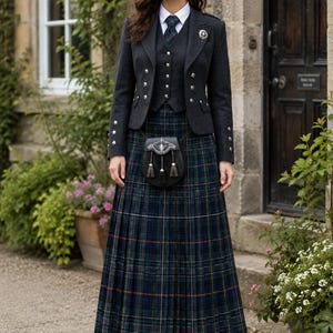 Può includere: Una giacca e un gilet in lana grigio antracite con bottoni argentati, indossati sopra una camicia bianca con colletto e una cravatta a quadri scuri. Una gonna lunga a pieghe in tartan blu navy, verde e rosso, con uno sporran in pelle nera con nappe.
