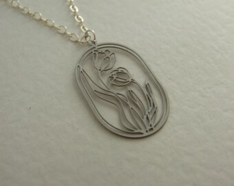 Puede incluir: Un collar de plata con un colgante que presenta un diseño recortado de dos tulipanes con tallos y hojas dentro de un marco ovalado.