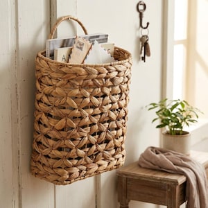Woven seaweed and water hyacinth hanging storage basket with metal frame and handle.
