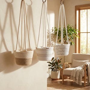 May include: A white ceramic mug with a black handle and the text "But First, Coffee" in a bold, black font. The mug is set against a blurred background, suggesting a cozy setting. The mug appears to be approximately 4 inches tall.