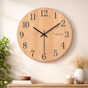 Könnte beinhalten: Eine runde Wanduhr aus hellem Holz mit schwarzen Ziffern und Zeigern. Das Zifferblatt hat ein helles Holzmaserungsmuster. Der Text "est 1863 old town clocks QUARTZ CLOCK" ist aufgedruckt.