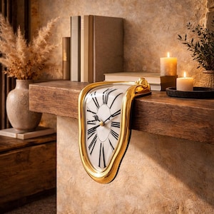 Pode incluir: Um relógio dourado e derretido com mostrador branco e algarismos romanos pretos. O relógio é exibido em uma prateleira de madeira, evocando uma estética surrealista. O design do relógio lembra uma pintura famosa.