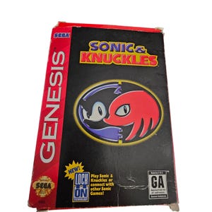 May include: A vintage SEGA Genesis video game box for Sonic & Knuckles. The box is black with the game title in yellow and red. The cover art features Sonic the Hedgehog and Knuckles the Echidna. The box is rated GA for general audiences.