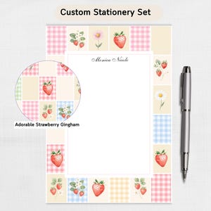 May include: Custom stationery set featuring a strawberry gingham design. The set includes a notepad with the name "Monica Nicole" and a silver pen. The notepad has a patchwork border with strawberries, daisies, and gingham patterns. The text "Adorable Strawberry Gingham" is also visible.