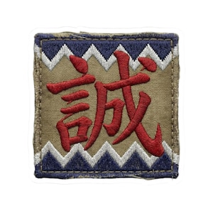May include: Square patch with a tan background and red Japanese characters. The patch has a blue and white zigzag border and a dark green border. The Japanese characters are in a bold, stylized font.