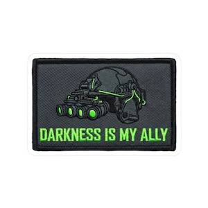 May include: Embroidered patch with a night vision device design in grey and green. The patch features the text "DARKNESS IS MY ALLY" in bright green. The patch is rectangular with a black border.