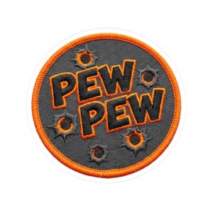 May include: Round patch with the words "PEW PEW" in black, outlined in orange, on a gray background. The patch has an orange border and several bullet hole designs. The patch is on a white background.