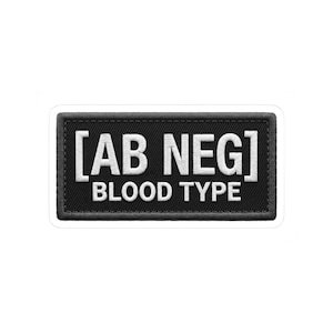 May include: A black rectangular patch with white embroidered text that reads "[AB NEG] BLOOD TYPE". The patch has a stitched border and is likely designed to be sewn onto clothing or bags.