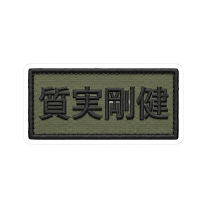 May include: Embroidered patch with Japanese characters in black on an olive green background. The patch has a black border and a white backing. The text is in a bold, sans-serif font.