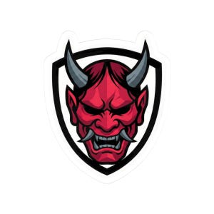 May include: A sticker featuring a red Oni mask design. The mask has gray horns, sharp teeth, and a stern expression. It is set against a black and white shield-shaped background, creating a bold graphic.
