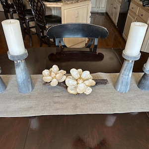 May include: A white ceramic mug with a black handle and the text "But First, Coffee" in a handwritten style. The mug is on a white surface. The mug is approximately 4 inches tall.