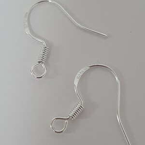 May include: Two silver-colored earring hooks. Each hook has a curved top, a coiled spring, and a small loop. The hooks are on a light gray background. The text "S925" is visible on one of the hooks.