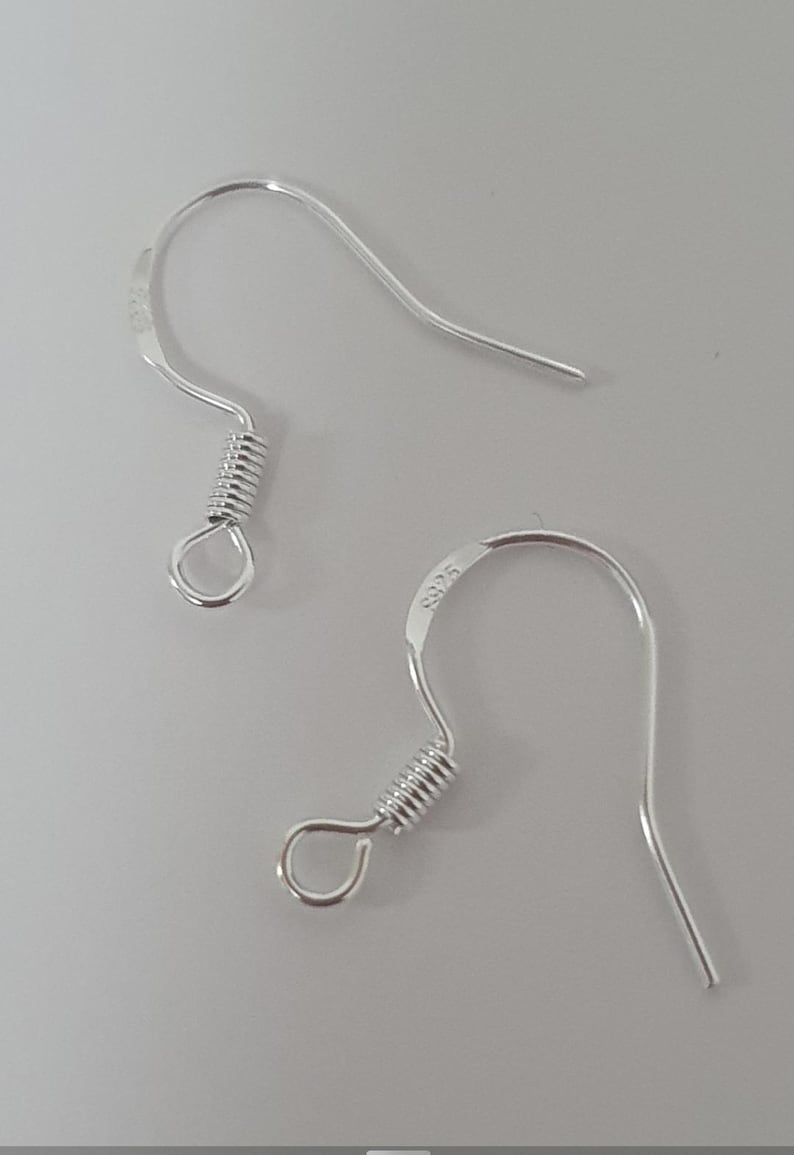 May include: Two silver-colored earring hooks. Each hook has a curved top, a coiled spring, and a small loop. The hooks are on a light gray background. The text "S925" is visible on one of the hooks.