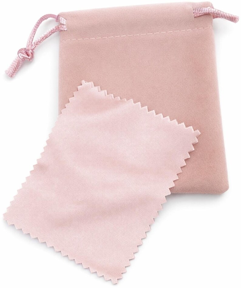 May include: A light pink velvet drawstring pouch with a matching pink satin cleaning cloth. The pouch has a knotted drawstring closure. The cleaning cloth has a zig-zag edge.