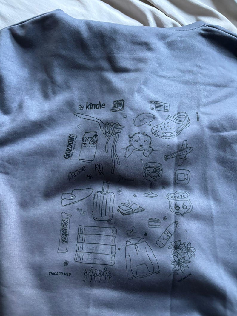 May include: Gray sweatshirt with a collection of illustrated icons including a Kindle, Coca-Cola can, pasta, a dog, a shoe, an airplane, a Route 66 sign, and more. The text "CHICAGO MED" is at the bottom.