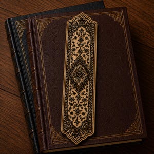 May include: A rectangular wooden bookmark featuring an intricate black laser-engraved floral and geometric pattern, resting on top of two hardcover books with dark brown and black textured covers and gold-toned decorative corner accents.