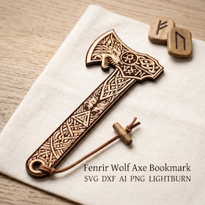 Puede incluir: Un marcapáginas de madera con forma de hacha, con intrincados grabados de un lobo y patrones de nudos celtas. El marcapáginas tiene un cordón de cuero y un pasador de madera. El texto "Fenrir Wolf Axe Bookmark" es visible.