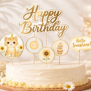 May include: A decorated cake with a gold "Happy Birthday" cake topper and several smaller toppers featuring a cat, sun, sunflower, and cupcakes. The cake is decorated with daisies and the phrase "Hello Sunshine!"