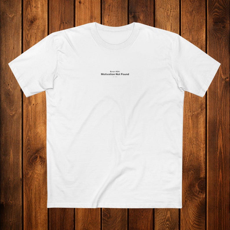 May include: Two white t-shirts are folded and stacked. The top shirt has the text "Error 404: Motivation Not Found" printed in black. The shirts are made of a soft material, likely cotton, and are neatly presented.