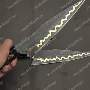 K&ouml;nnte beinhalten: Zwei handgefertigte Messer mit dunklen Klingen und goldfarbenen, wellenf&ouml;rmigen Akzenten. Die Griffe sind dunkelbraun. Die Messer werden vor einem dunklen Hintergrund pr&auml;sentiert. Der Text "Nordic Edge Forge" ist im Hintergrund sichtbar.