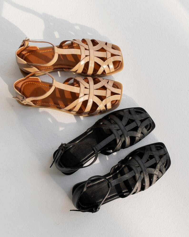 May include: Two pairs of sandals. The top pair is tan with a woven design and brown soles. The second pair is also tan with a woven design and brown soles. The bottom pair is black with a woven design and black soles. The fourth pair is black with a woven design and black soles.