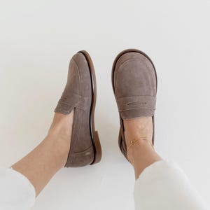 Detailed close-up shot of hand-stitched sand-colored suede on a classic penny loafer, highlighting the premium texture