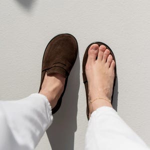 Comparison of a natural bare foot next to the wide toe box brown suede loafer, showing the healthy anatomical fit