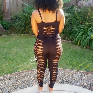 Pode incluir: Leggings pretos com recortes e um top preto sem mangas com costas de renda.