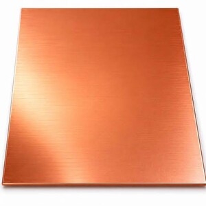 May include: A rectangular metal sheet with a brushed copper finish. The surface features a distinct horizontal grain pattern that reflects light, creating a warm, metallic orange-brown appearance across the flat, smooth, and uniform panel.