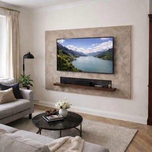 Puede incluir: Salón moderno con un televisor de pantalla plana grande montado en la pared. Una estantería de madera oscura está debajo del televisor. Un sofá gris, una mesa de centro redonda y una alfombra completan la decoración. También se ven una lámpara de pie negra y un jarrón con flores blancas.