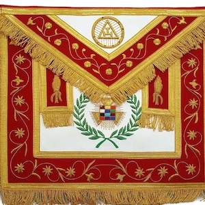 Könnte beinhalten: Eine rot-weiße Freimaurerschürze mit goldener Fransen und Stickerei. Die Schürze hat eine zentrale weiße Tafel mit einem Kranz und geometrischem Design sowie einen goldverzierten roten Rand mit Blumen- und Sternmustern.