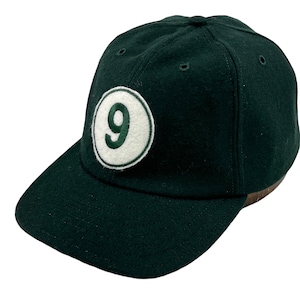 Puede incluir: Una gorra de béisbol verde oscuro con un círculo blanco y el número "9" bordado en verde.
