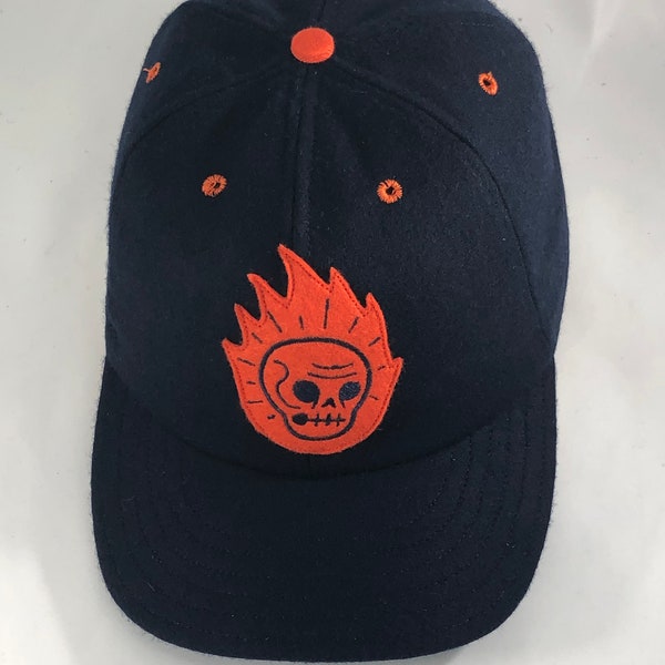 Flaming skull felt patch, art by Ryan Hungerford. Navy melton wool cap 6 panel with 2.5” visor. Any size available.