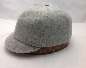 May include: A gray wool baseball cap with a curved brim. The cap is on a wooden form.