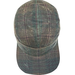 Puede incluir: Una gorra de béisbol de cuadros verdes y marrones con visera curva.