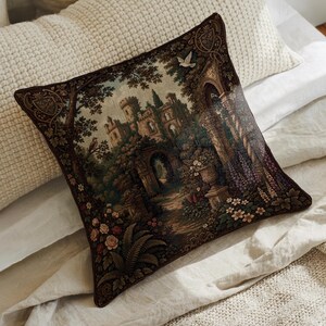 May include: A square throw pillow featuring a detailed tapestry-style print of a stone castle surrounded by lush trees, garden arches, and blooming flowers in shades of brown, green, and purple, with a small white bird flying in the sky.