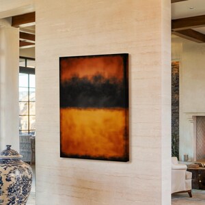 Può includere: Dipinto astratto con una fascia nera su sfumature di arancione e giallo. L'opera d'arte è esposta su una parete bianca in un ambiente interno moderno. Il dipinto ha un bordo scuro e un aspetto strutturato.