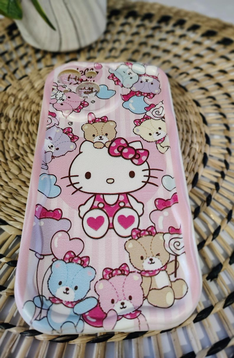 May include: Pink phone case featuring Hello Kitty and teddy bear illustrations. The case has a vertical striped background with hearts, bows, and clouds. The design includes blue, pink, and brown teddy bears and Hello Kitty.