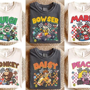 May include: Six t-shirts featuring Nintendo Mario Kart characters: Luigi, Bowser, Mario, Donkey Kong, Daisy, and Peach. Each shirt displays the character driving a go-kart over a checkered background with game icons like coins, mushrooms, and shells.