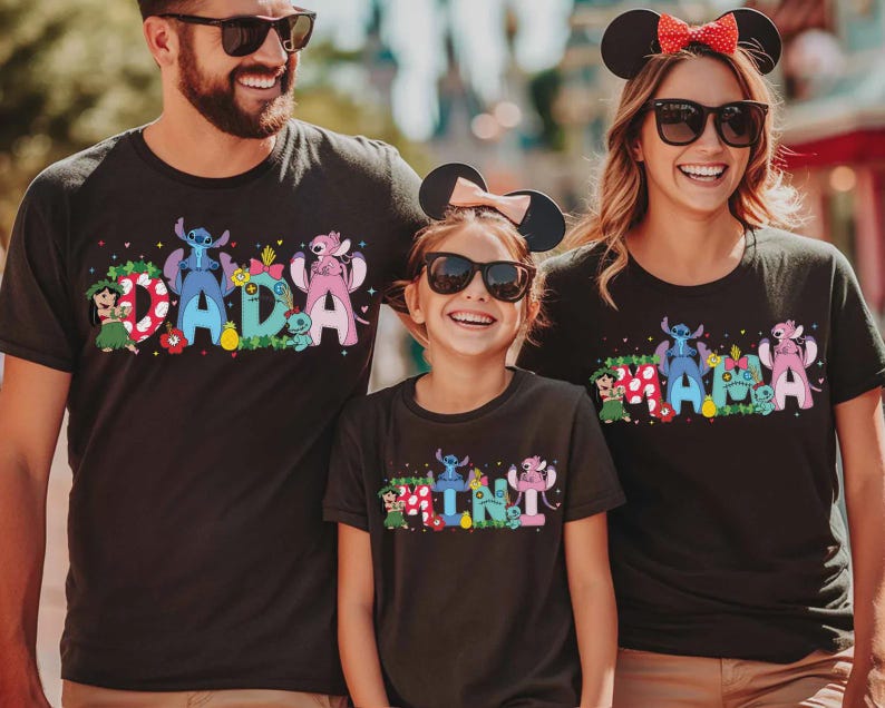 Puede incluir: Tres camisetas negras con gr&aacute;ficos coloridos. Las camisetas presentan las palabras "DADA", "MAMA" y "MINI" con personajes de dibujos animados. Las camisetas son usadas por una familia, cada uno con gafas de sol y orejas de rat&oacute;n.