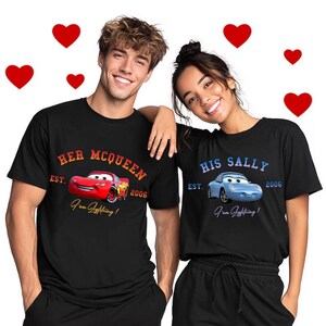 May include: Black t-shirts with car graphics. One shirt says "Her McQueen" with a red car, and the other says "His Sally" with a blue car. Both shirts have the text "I'm Lightning!" and the year 2006.