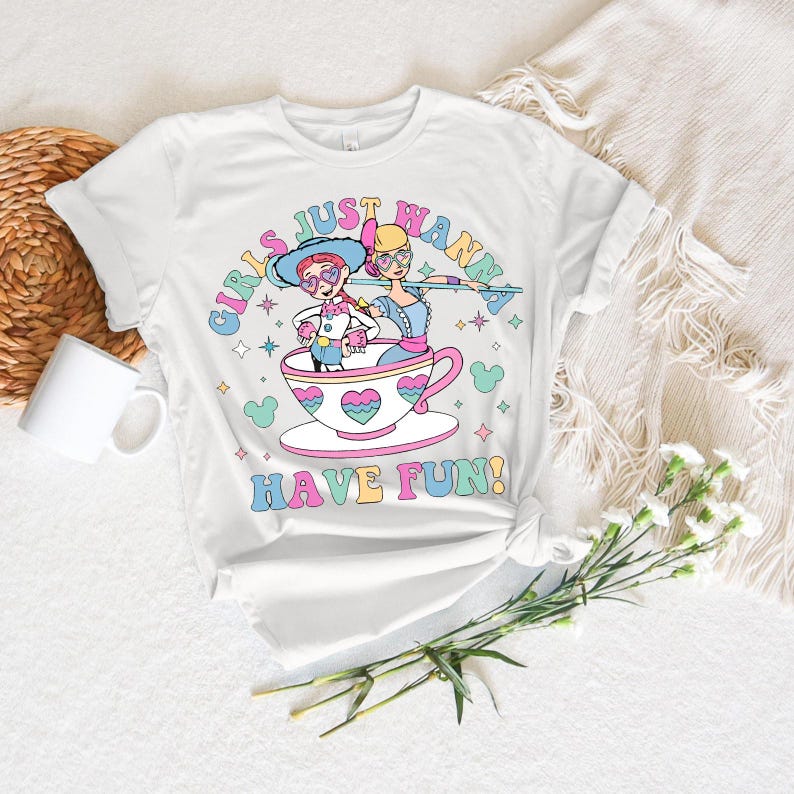 May include: White t-shirt with a cartoon graphic of two characters in a teacup, and the text "GIRLS JUST WANNA HAVE FUN!". The design uses pastel colours and star shapes.