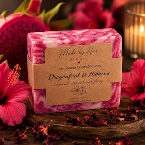 May include: A handmade goat milk soap bar with dragonfruit and hibiscus. The soap is pink and white, wrapped with a brown paper label that reads "Made by Her Studio". The bar weighs approximately 4.5 oz.
