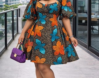 May include: A knee-length dress with a black background and a floral pattern in orange and blue. The dress has a keyhole neckline and short, puffed sleeves. A purple handbag and silver heels complete the look. The text "Mof couture" is visible.