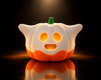 Op de afbeelding: Een wit en oranje pompoenvormige lamp met een spookachtig silhouet. Het bovenste gedeelte is wit met twee ovale ooguitsparingen en een ronde mondopening, terwijl het onderste gedeelte oranje is. Een kleine groene steel zit bovenop de pompoen.