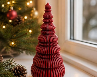 Op de afbeelding: Een conisch decoratief object in de vorm van een kerstboom, opgebouwd uit gestapelde, verticaal geribbelde rode cirkelvormige schijven die in grootte afnemen naar de puntige bovenkant. Het object heeft een gladde, matte afwerking en een symmetrisch silhouet.