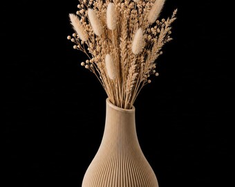 Op de afbeelding: Een beige vaas met een verticale geribbelde textuur gevuld met een droogbloemenarrangement. Het boeket bestaat uit lichtbruine hazenstaartjes, tarwearen en kleine ronde zaaddoosjes in een natuurlijk, gedempt en monochroom kleurenpalet.