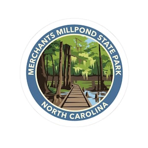 May include: A circular sticker featuring a graphic illustration of a wooden boardwalk leading into a swampy forest with cypress trees and hanging moss. The blue border contains the text MERCHANTS MILLPOND STATE PARK NORTH CAROLINA in white.