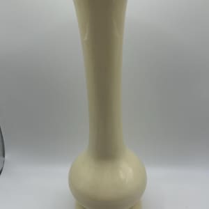 May include: A tall, cream-colored ceramic vase with a bulbous midsection and a flared top. The vase has a rounded base and a smooth, glossy finish. It is a decorative item suitable for displaying flowers or as a standalone accent piece.